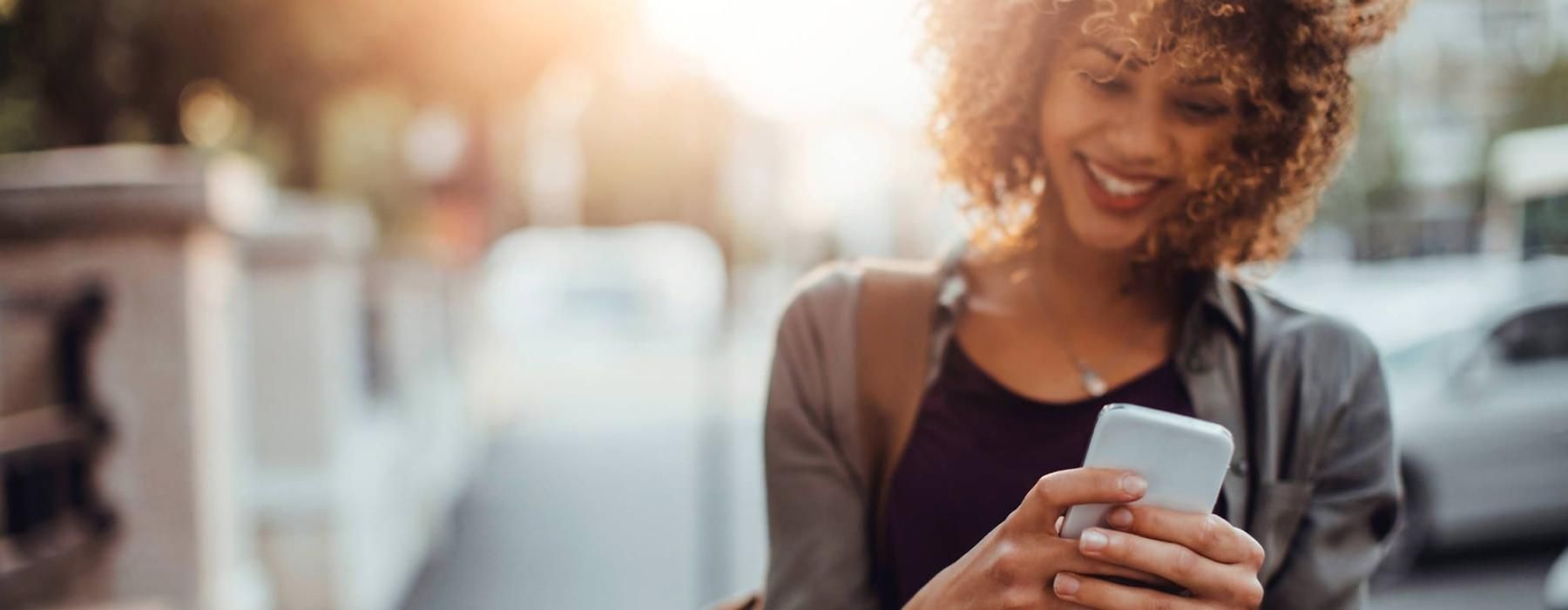 woman texts on her phone as she walks through the city