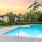 a swimming pool with palm trees and buildings in the background